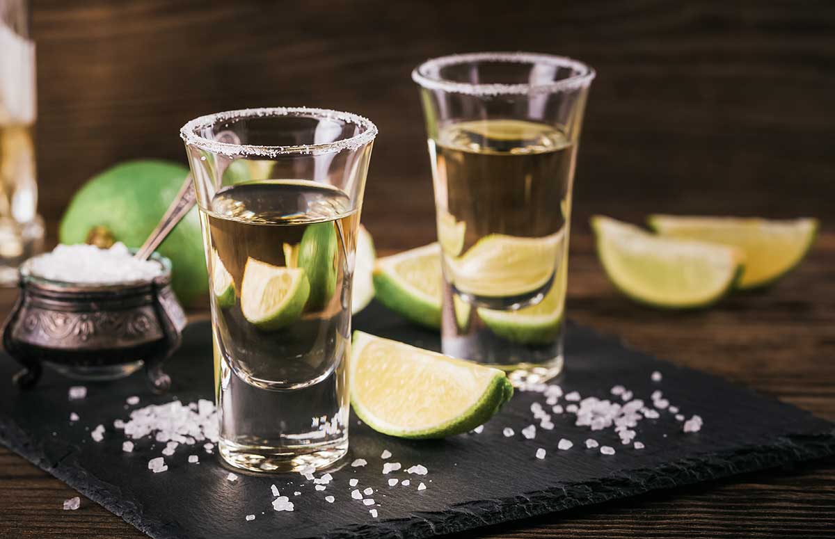 reposado tequila in two shot glasses with limes and salt
