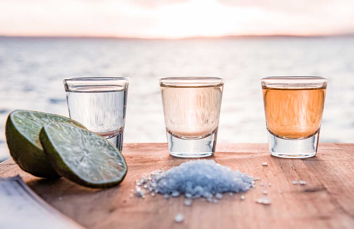 three shot glasses with different types of tequila