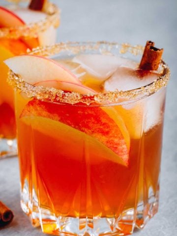 two glasses of apple margarita with a cinnamon stick