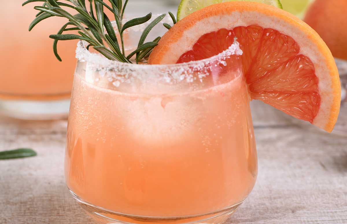 a glass of mezcal paloma and one grapefruit on the side. 