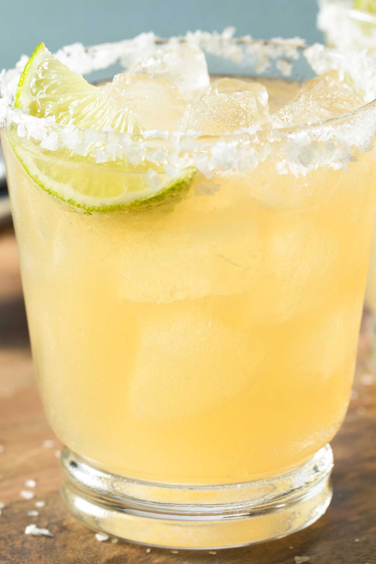 Close up of a rimmed glass of skinny margarita with a lime wedge.