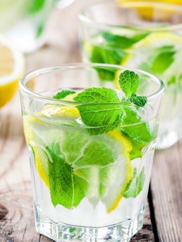 lemon lime margarita inside a glass with fresh mint and lemon wedge