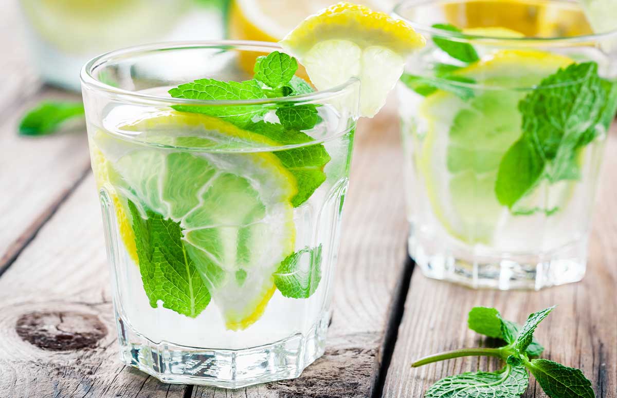 two glasses of lemon lime margarita with fresh mint and lemon wedge