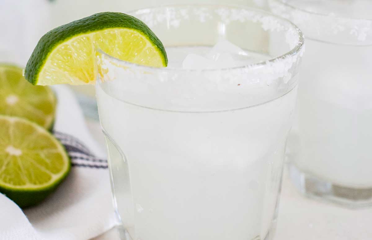 a closeup of a salt rimmed glass of a margarita with a lime wedge