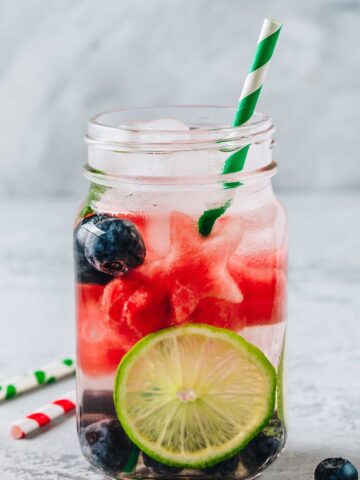 red white and blue margarita recipe with blueberries and watermelon in a glass with a lime