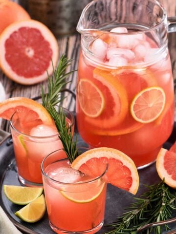 pitcher of Paloma cocktails with grapefruit wedges and lime wedges