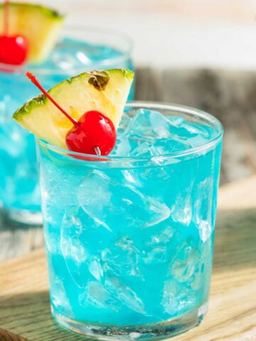 Blue Hawaiian Margarita in a glass with a pineapple and cherry garnish