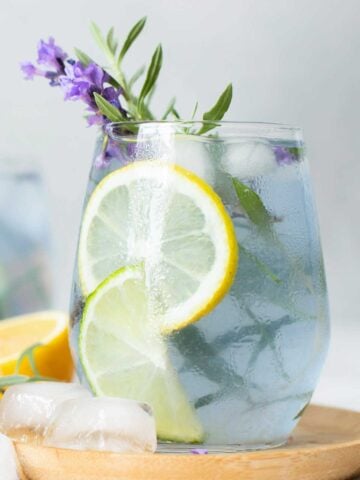 Lavender Margarita in a glass with lavender sprigs and lime slices