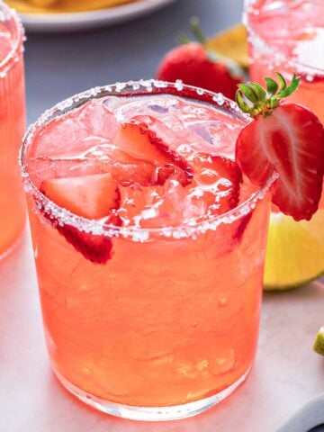 Strawberry Margarita on the rocks with a salted rim and strawberry garnishes