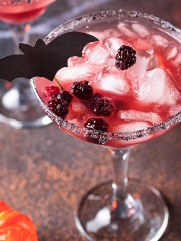 Spooky Blackberry Margarita with blackberries, sugared rim, and a bat for decoration