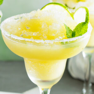 Two glasses of Frozen Skinny Margaritas with lime slices and mint.