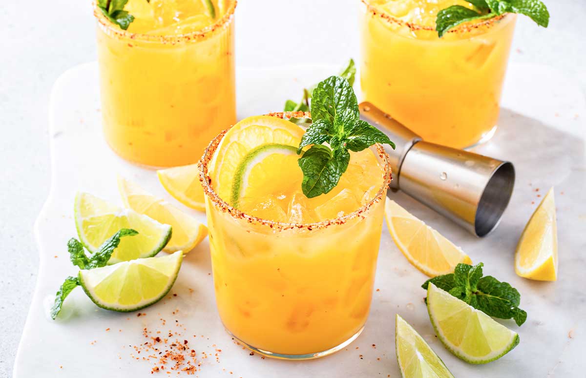 Skinny Orange Margarita with Tajin rim, orange and lime slices, and mint sprig.