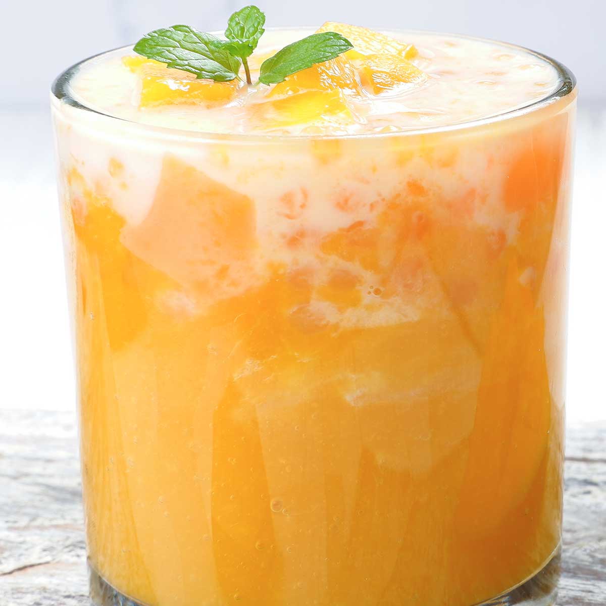 Skinny mango margarita with mango slices and mint sprig.