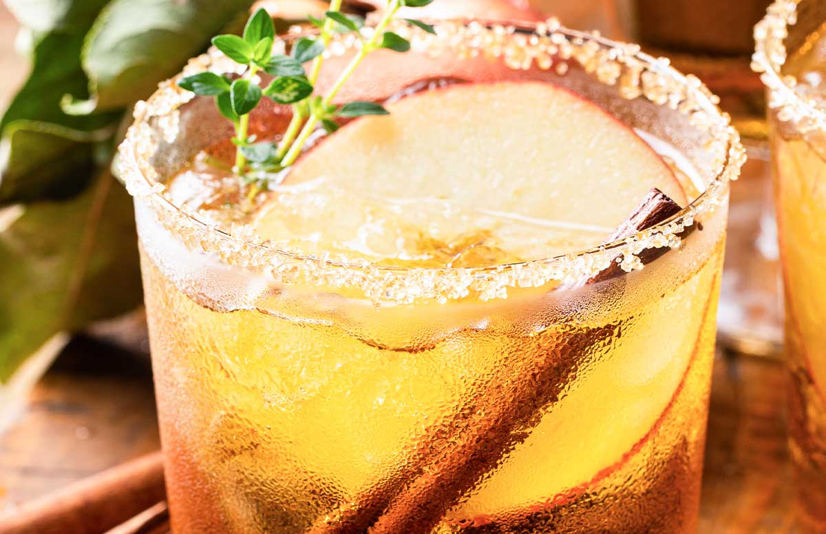 Fall Margarita with a brown sugar rim, apple slices, and cinnamon sticks.