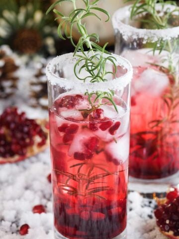 Christmas cocktail with tequila, with a salted rim, thyme, and pomegranate seeds.