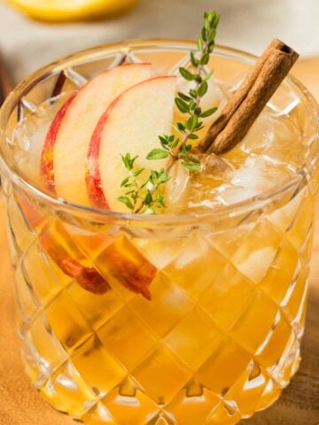 cinnamon margarita with apple slices and cinnamon sticks.
