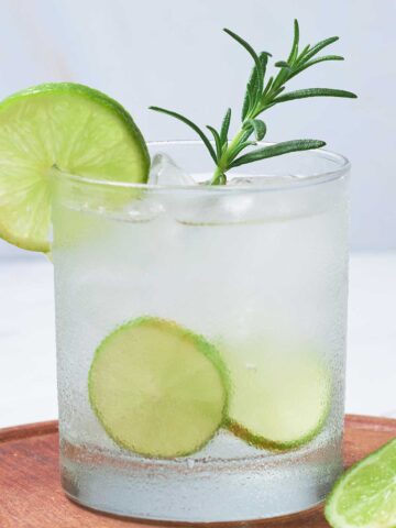 Rosemary Margarita with rosemary sprig and lime wedges.