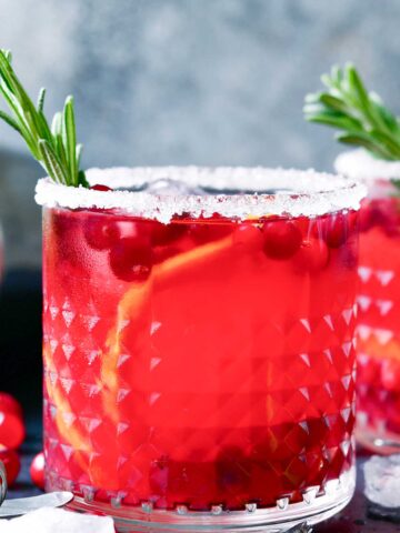 skinny Christmas Margarita with a sugared rim, orange slices, and cranberries.