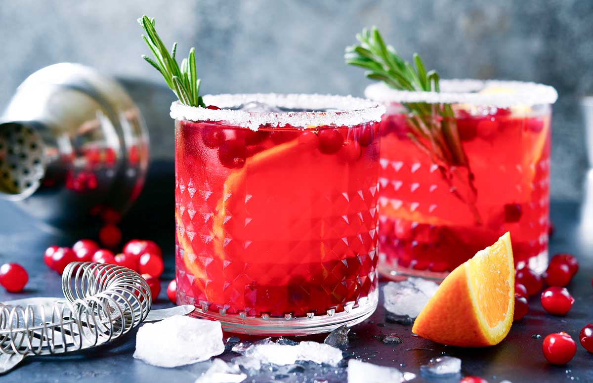 skinny Christmas Margarita with a sugared rim, orange slices, and cranberries.