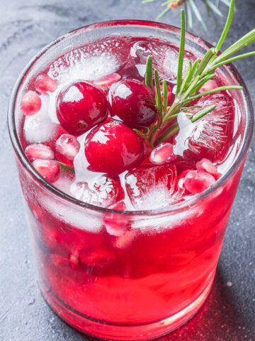 skinny pomegranate margarita with cranberries and rosemary sprig.