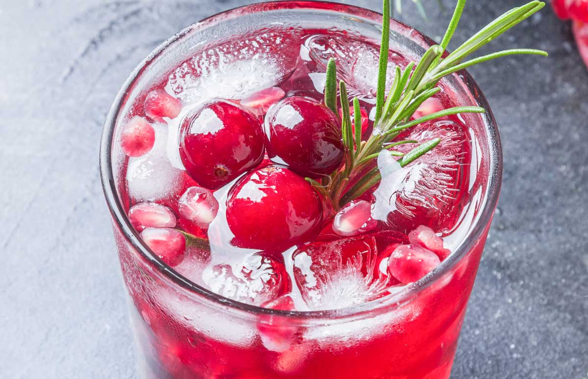 skinny pomegranate margarita with cranberries and rosemary sprig.