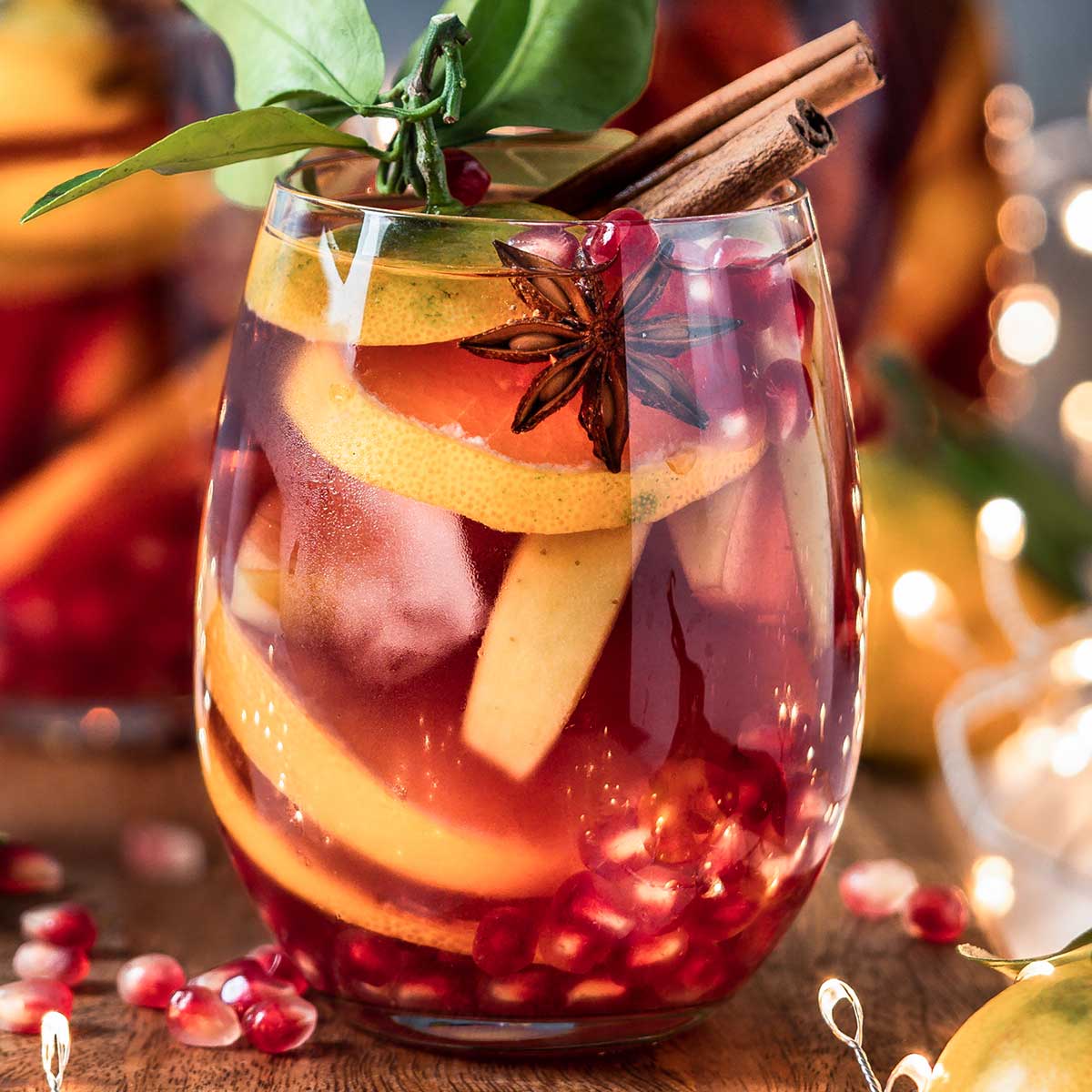 winter tequila sangria with orange slices, cinnamon sticks, star anise and pomegranate seeds.