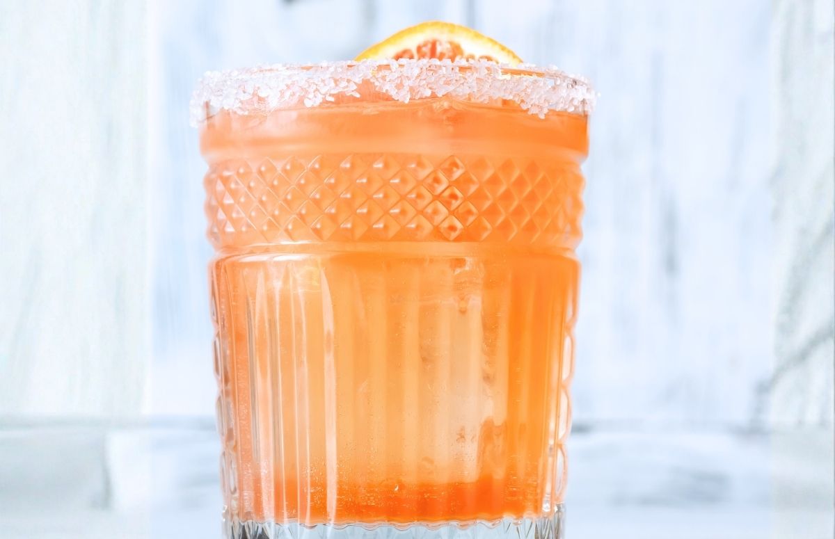skinny blood orange margarita in a low ball glass with a salted rim and a blood orange slice