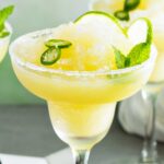 Spicy Frozen Margarita with a salted rim and lime slices and jalapeno rounds