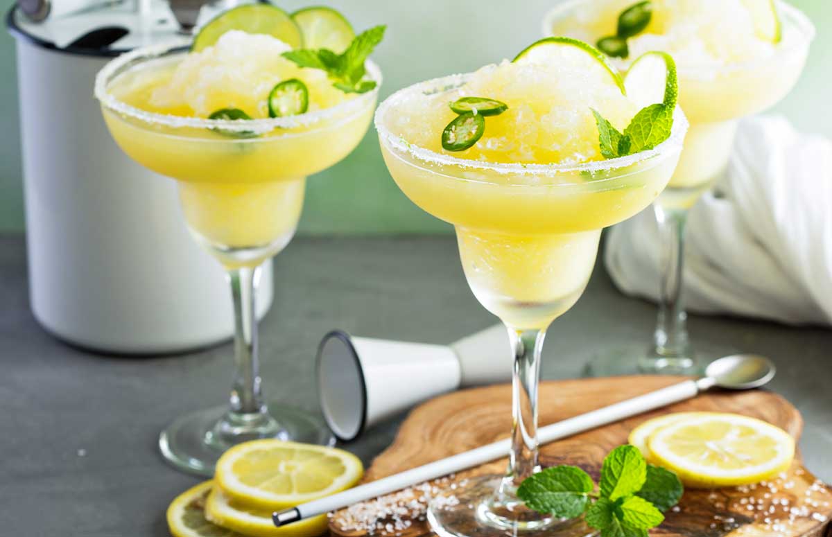 Spicy Frozen Margarita with a salted rim and lime slices and jalapeno rounds