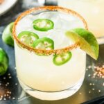 spicy margarita with jalapenos, lime wedges, and a tajin-coated rim