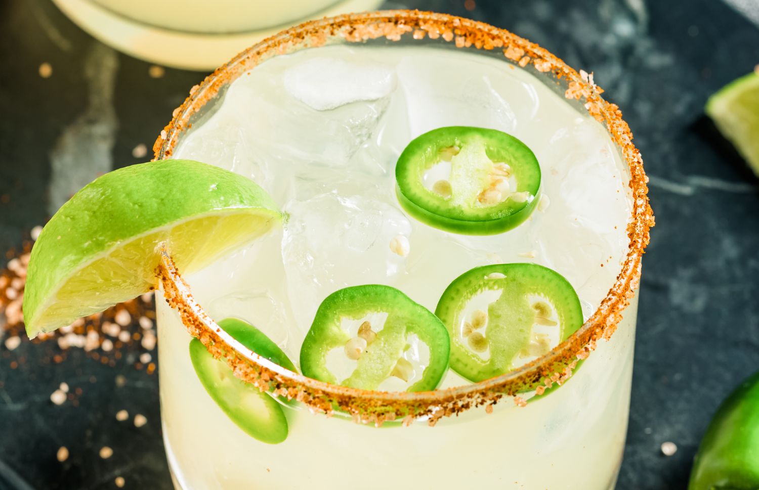 spicy margarita with jalapenos, lime wedges, and a tajin-coated rim
