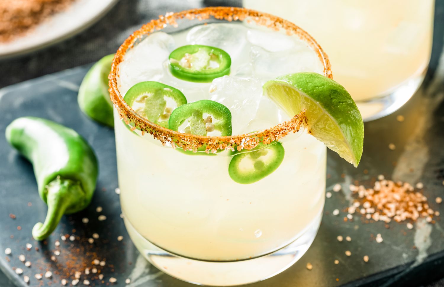 spicy margarita with jalapenos, lime wedges, and a tajin-coated rim