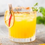 spicy orange margarita in a glass rimmed with tajin
