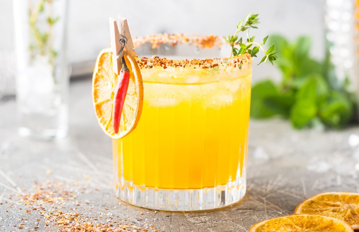 spicy orange margarita in a glass rimmed with tajin