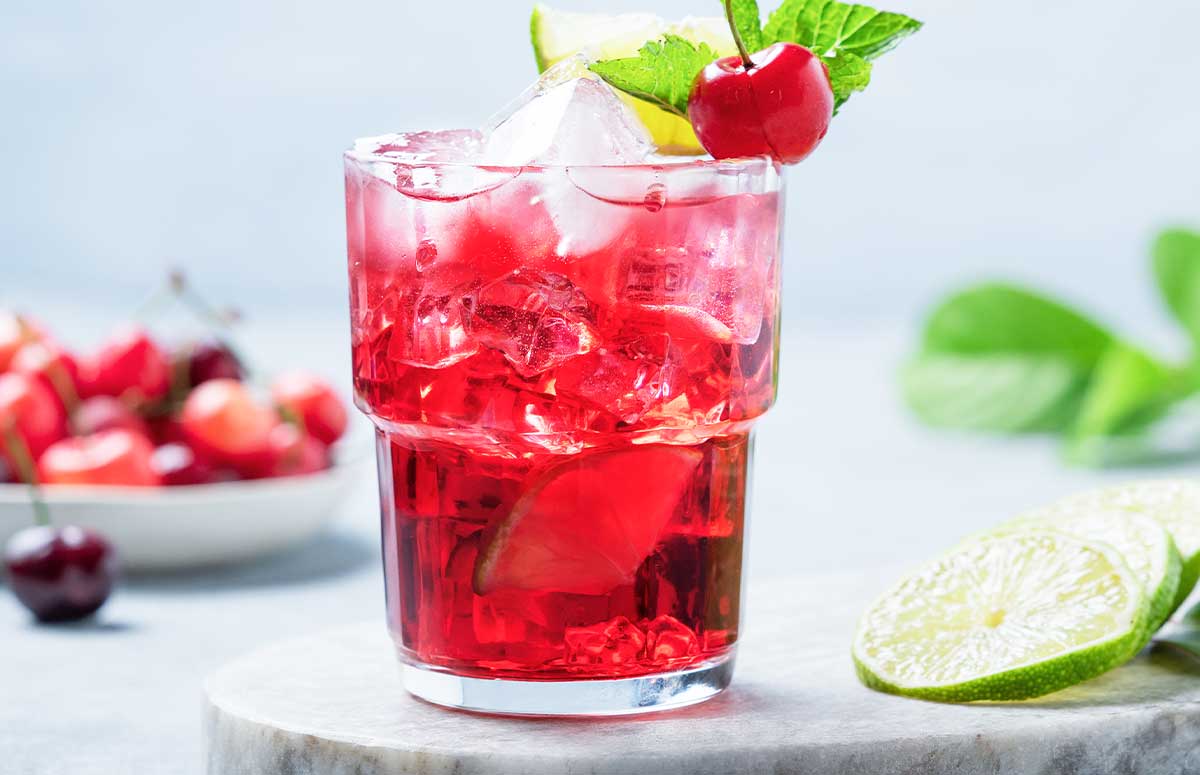 dirty shirley cocktail with a plate of cherries and sliced limes