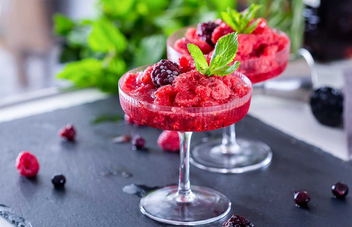 two frozen berry margaritas garnished with mint leaves