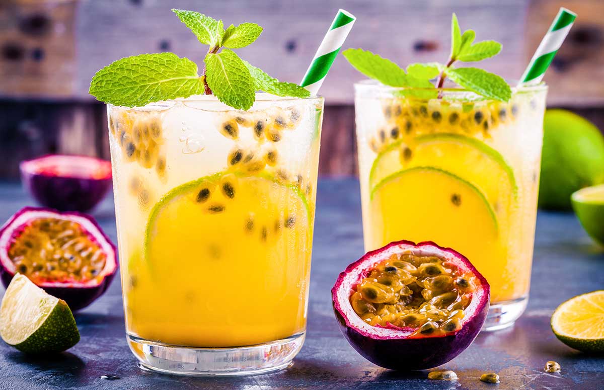 two glasses of passion fruit margaritas garnished with green leaves