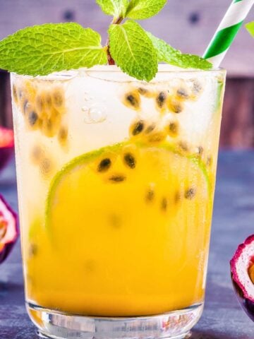 small glass of an orange passion fruit margarita garnished with a striped green straw