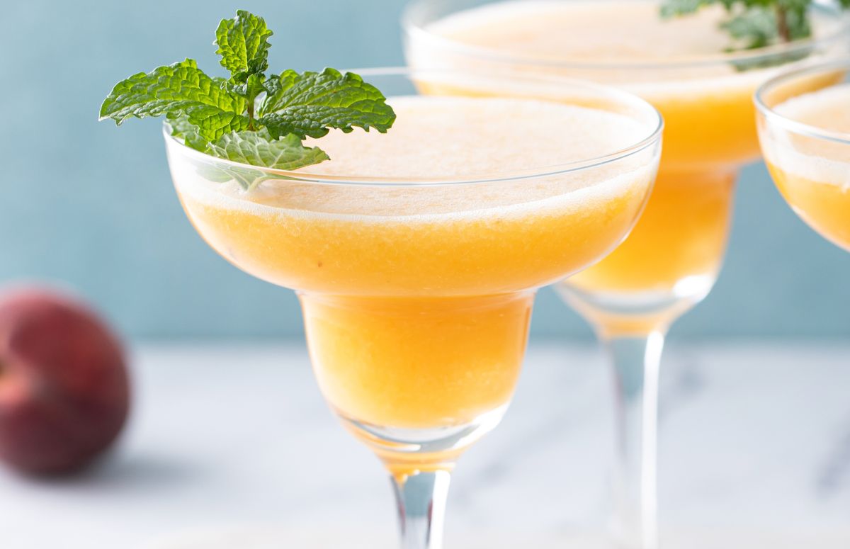 two frozen peach margaritas in long stem margarita glasses