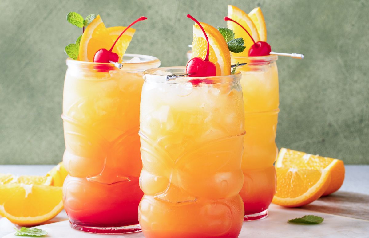 three tall glasses of tequila punch topped with fruit